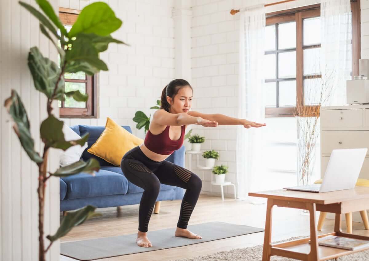 A woman doing an online cardio yoga class at home .