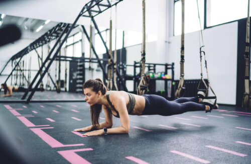 woman using trx equipment for a forearm plank at a gym