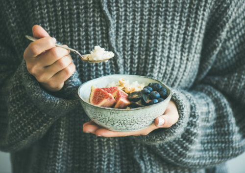 healthy breakfast; person in knitted jumper with bowl of fruit