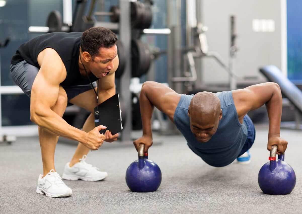 A man doing push-ups with his personal trainer.