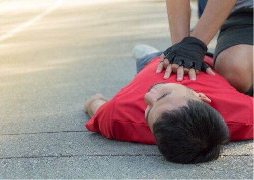 another man lying on the floor with someone administrating CPR with gloves on