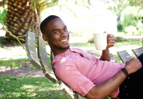 man chilling in the garden with a cup of coffee smiling and resting