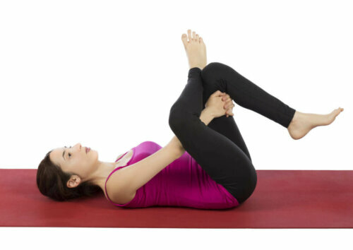 wind-relieiving pose woman on a yoga mat