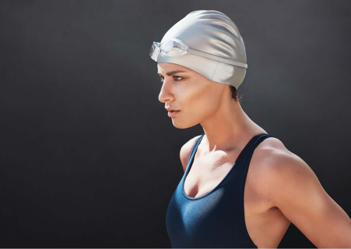 woman contemplating her game plan about to swim wearing swimming cap and bathing suit
